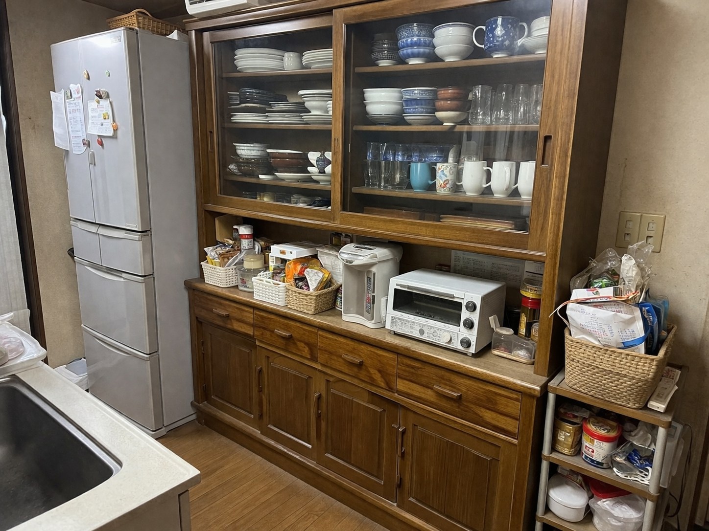 収納不足で物があふれた昔ながらの食器棚とキッチンの様子